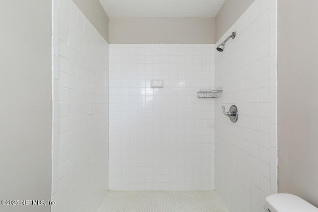 bathroom featuring toilet, a textured ceiling, and a tile shower