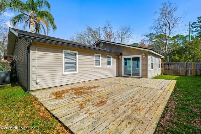 rear view of house with cooling unit, a wooden deck, and a yard