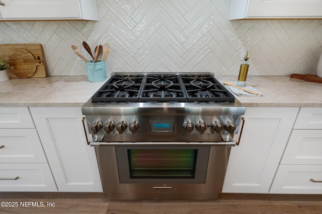 details with white cabinets, high end stainless steel range, and decorative backsplash