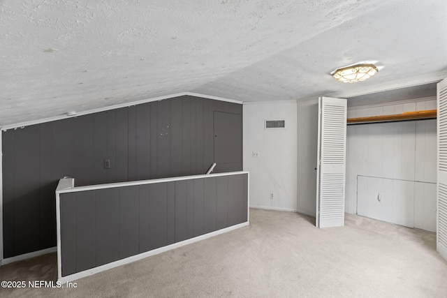 interior space featuring vaulted ceiling, light colored carpet, and a textured ceiling