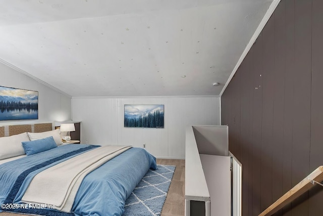 bedroom with hardwood / wood-style floors, crown molding, and vaulted ceiling