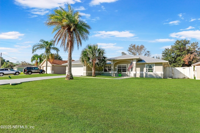 view of front of property featuring metal roof, an attached garage, driveway, stucco siding, and a front lawn