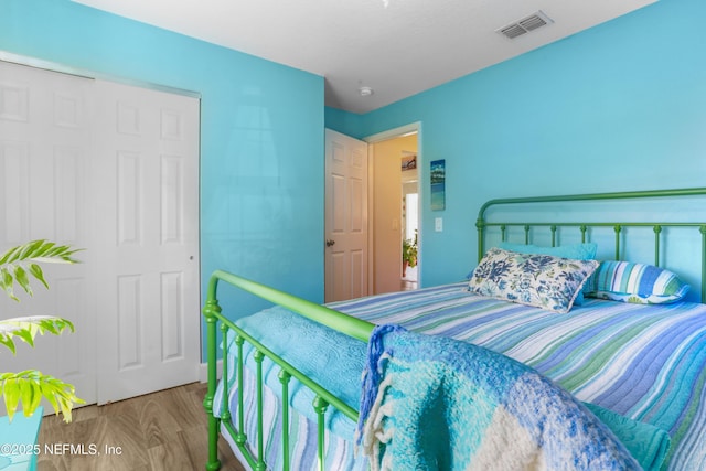 bedroom featuring visible vents and wood finished floors