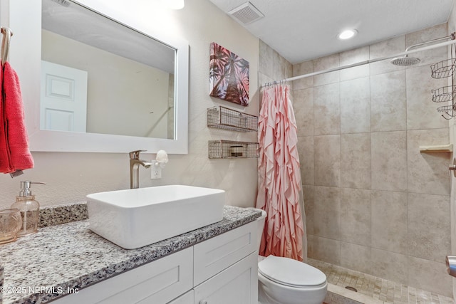 full bathroom featuring a stall shower, visible vents, vanity, and toilet