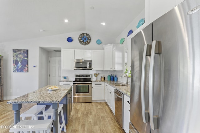 kitchen featuring stainless steel appliances, a sink, white cabinetry, and light stone countertops