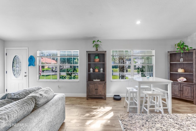 living room featuring light wood-type flooring, baseboards, and recessed lighting