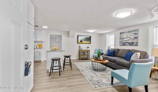 living room featuring light wood-style flooring, baseboards, and a textured ceiling