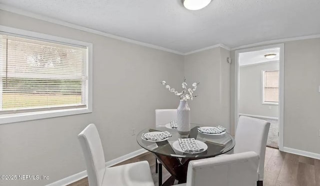 dining room featuring baseboards, wood finished floors, and crown molding