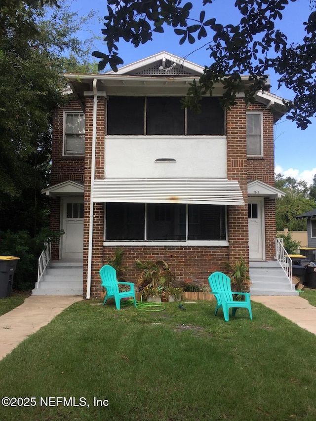 view of front of property featuring brick siding and a front yard