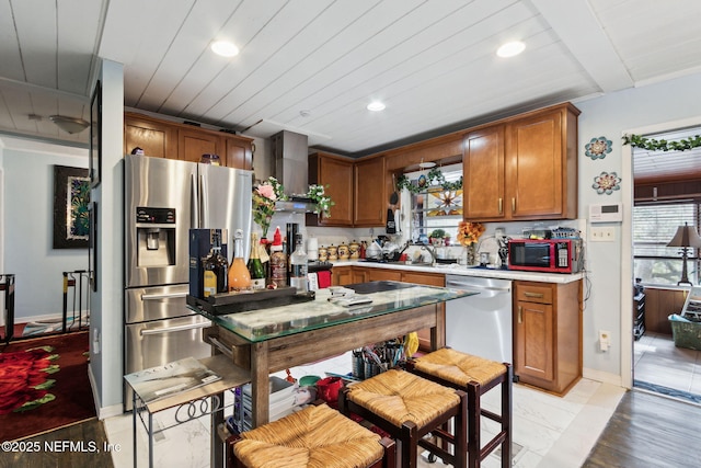 kitchen with wood ceiling, a wealth of natural light, stainless steel appliances, and wall chimney exhaust hood