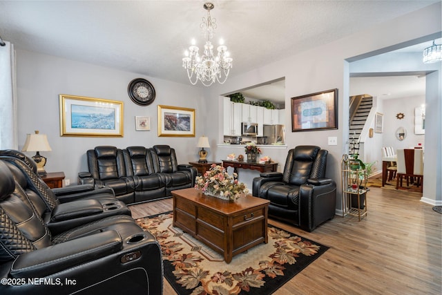 living room with baseboards, light wood-type flooring, and an inviting chandelier