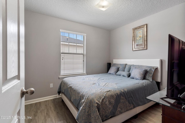 bedroom with a textured ceiling, baseboards, and wood finished floors