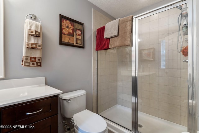 full bath featuring toilet, a stall shower, a textured ceiling, and vanity