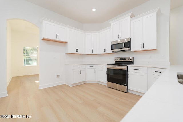 kitchen with white cabinetry, light wood-type flooring, and appliances with stainless steel finishes