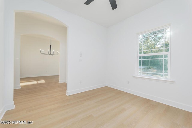 unfurnished room featuring hardwood / wood-style flooring and ceiling fan with notable chandelier