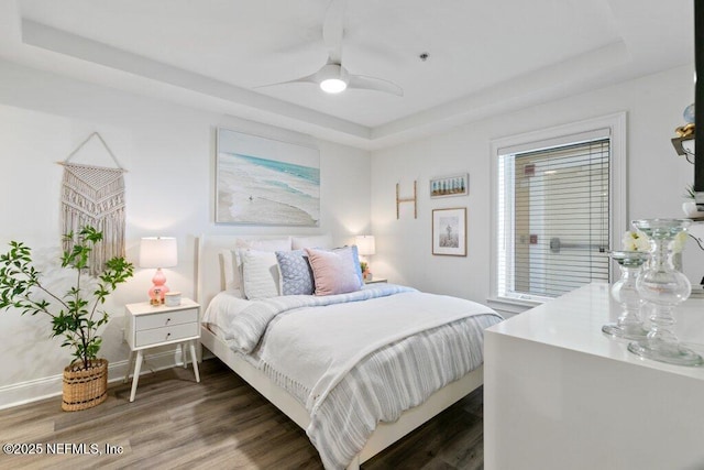 bedroom featuring a raised ceiling, ceiling fan, and dark hardwood / wood-style flooring