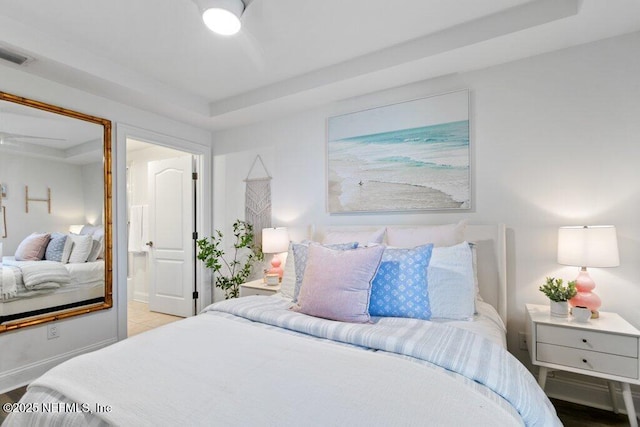 bedroom with a tray ceiling and connected bathroom