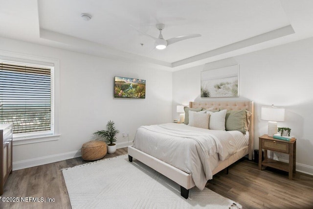 bedroom featuring hardwood / wood-style flooring, ceiling fan, and a tray ceiling