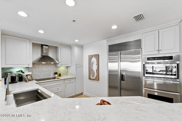 kitchen featuring white cabinetry, sink, stainless steel appliances, and wall chimney exhaust hood