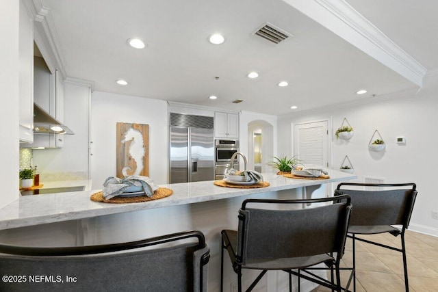 kitchen with white cabinetry, ornamental molding, stainless steel appliances, and kitchen peninsula