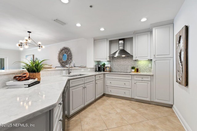 kitchen with sink, light stone counters, tasteful backsplash, hanging light fixtures, and wall chimney range hood