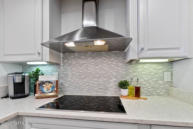 kitchen with white cabinetry, black electric cooktop, tasteful backsplash, and wall chimney range hood