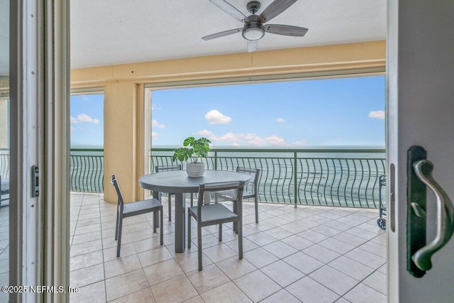 interior space featuring light tile patterned flooring, a water view, and ceiling fan