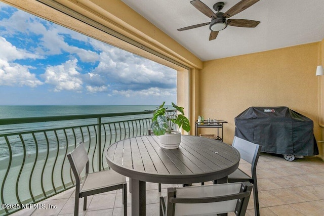 balcony with a view of the beach, grilling area, ceiling fan, and a water view