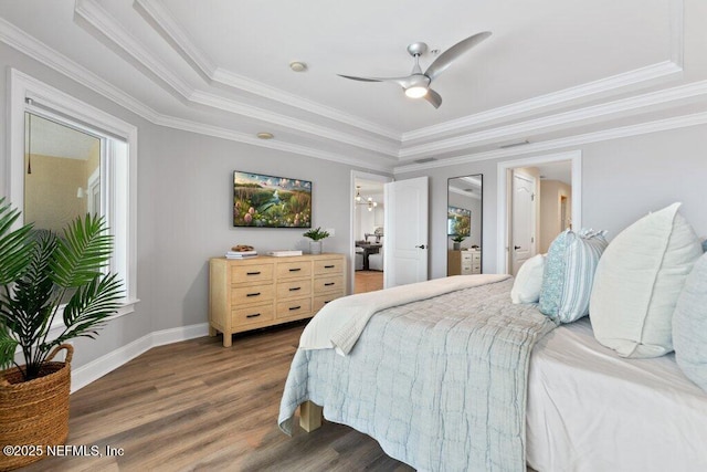 bedroom featuring a raised ceiling, ornamental molding, dark hardwood / wood-style floors, and ceiling fan