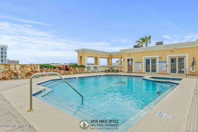 view of swimming pool featuring a community hot tub and a patio