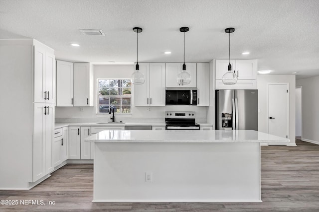 kitchen with sink, stainless steel appliances, white cabinets, and a kitchen island