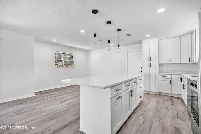 kitchen with white cabinetry, a center island, pendant lighting, and light hardwood / wood-style floors