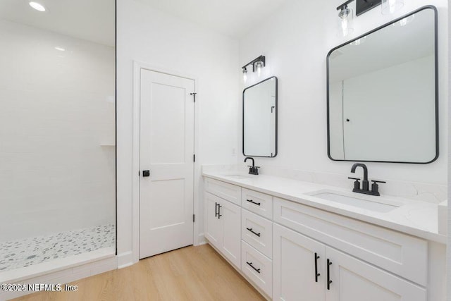 bathroom featuring vanity, hardwood / wood-style floors, and a tile shower