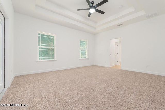 carpeted empty room with a raised ceiling and ceiling fan