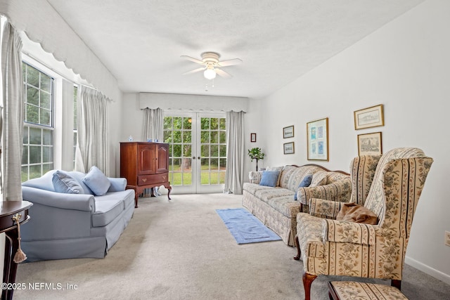 living room with french doors, light colored carpet, ceiling fan, and a textured ceiling