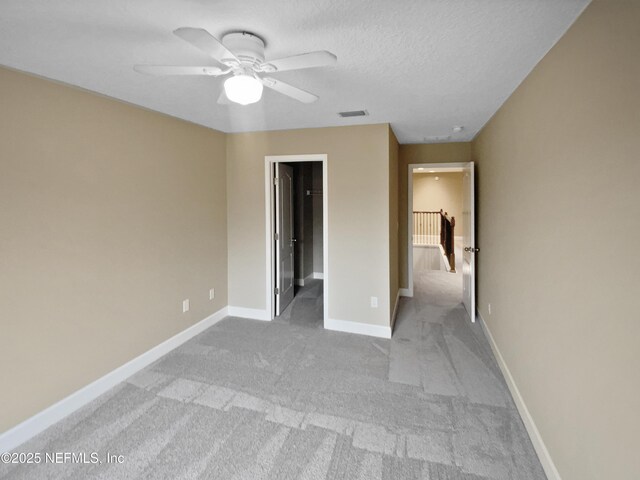 unfurnished bedroom with light carpet, ceiling fan, and a textured ceiling