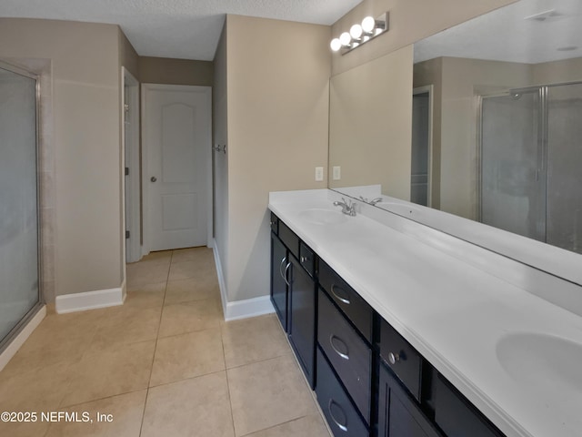 bathroom with a textured ceiling, vanity, tile patterned flooring, and an enclosed shower