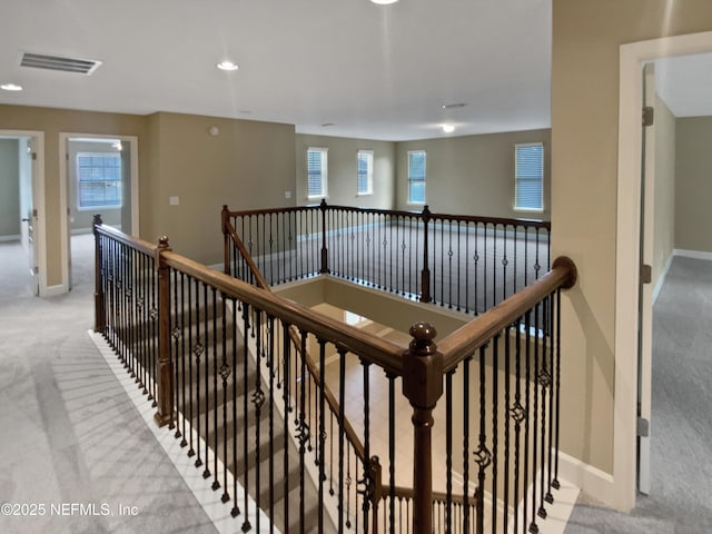 corridor featuring light colored carpet and a wealth of natural light