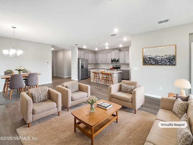 living room featuring a notable chandelier, light hardwood / wood-style flooring, and sink