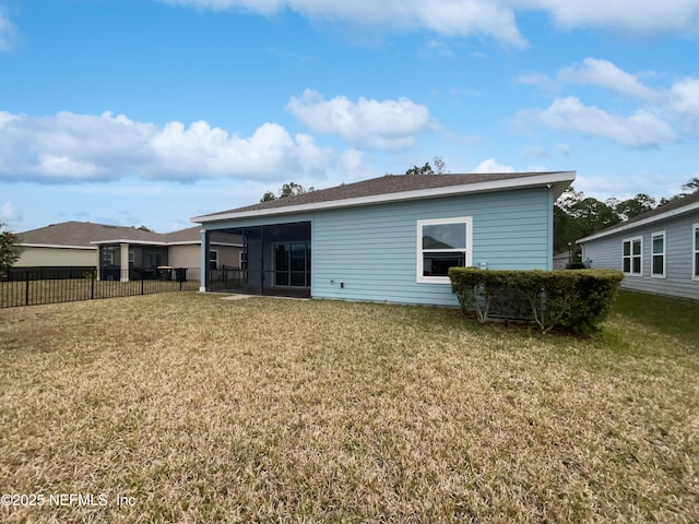 rear view of house with a yard and a sunroom