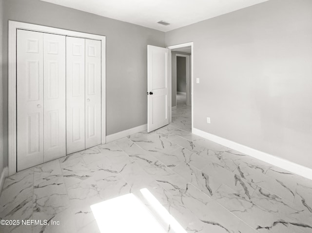 unfurnished bedroom featuring a closet, marble finish floor, visible vents, and baseboards