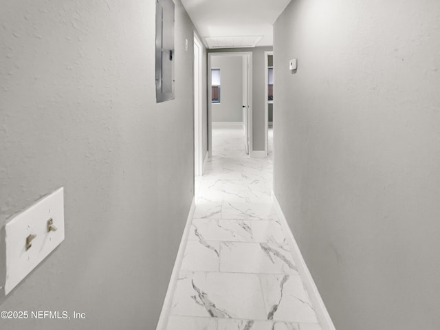 hallway featuring marble finish floor, electric panel, and baseboards