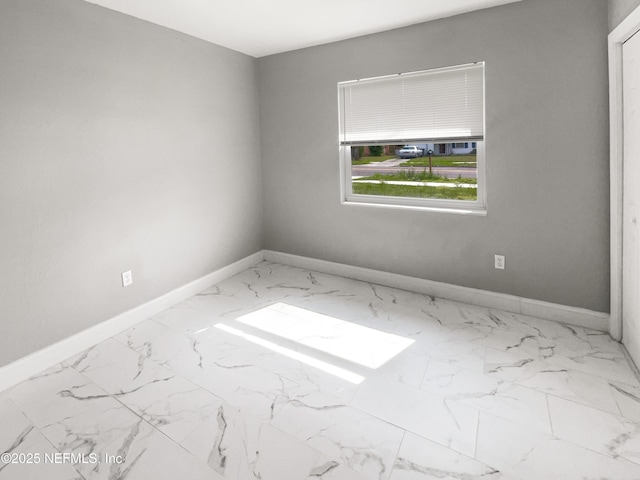 unfurnished room featuring marble finish floor and baseboards