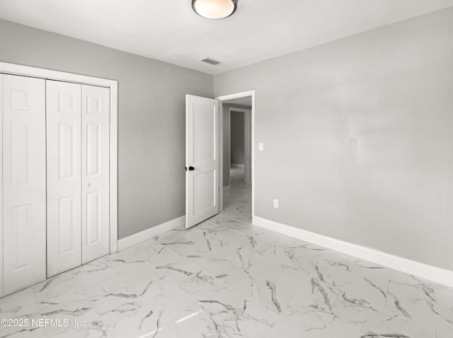 unfurnished bedroom with marble finish floor, visible vents, baseboards, and a closet