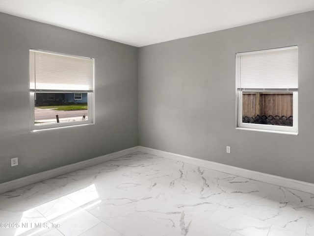 empty room featuring marble finish floor and baseboards