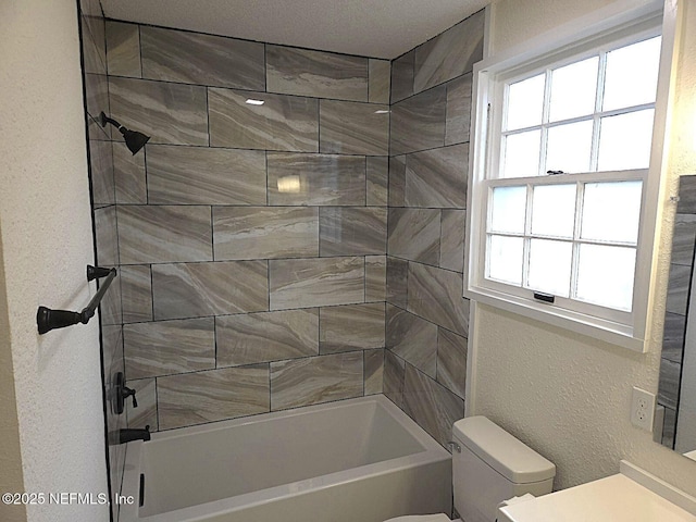 full bathroom featuring tiled shower / bath, vanity, and toilet