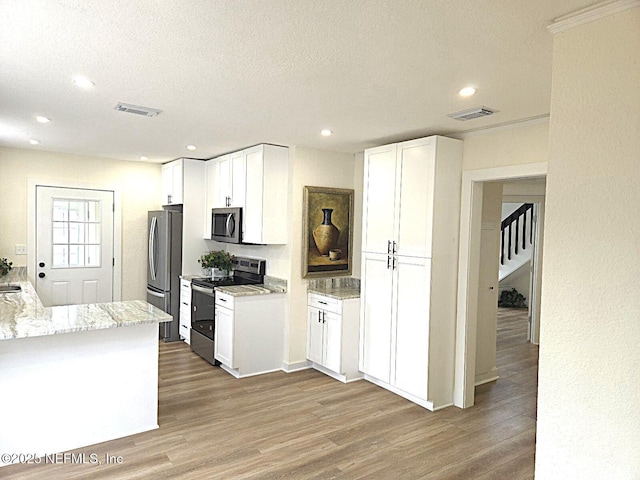 kitchen featuring stainless steel appliances, white cabinetry, light stone counters, and light hardwood / wood-style flooring