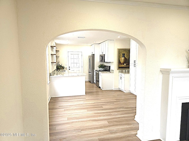 hallway featuring ornamental molding and light wood-type flooring