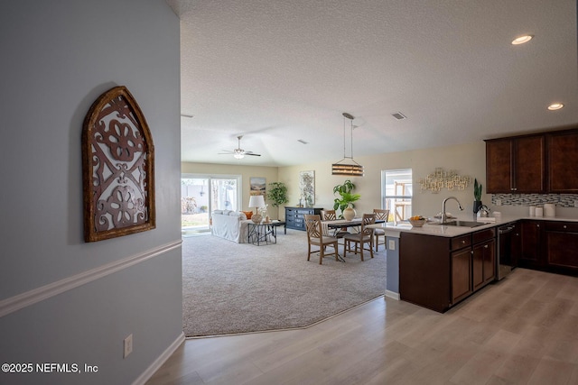 kitchen featuring decorative light fixtures, dishwasher, sink, dark brown cabinetry, and kitchen peninsula