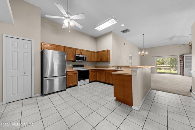 kitchen featuring brown cabinetry, a peninsula, appliances with stainless steel finishes, ceiling fan with notable chandelier, and open floor plan